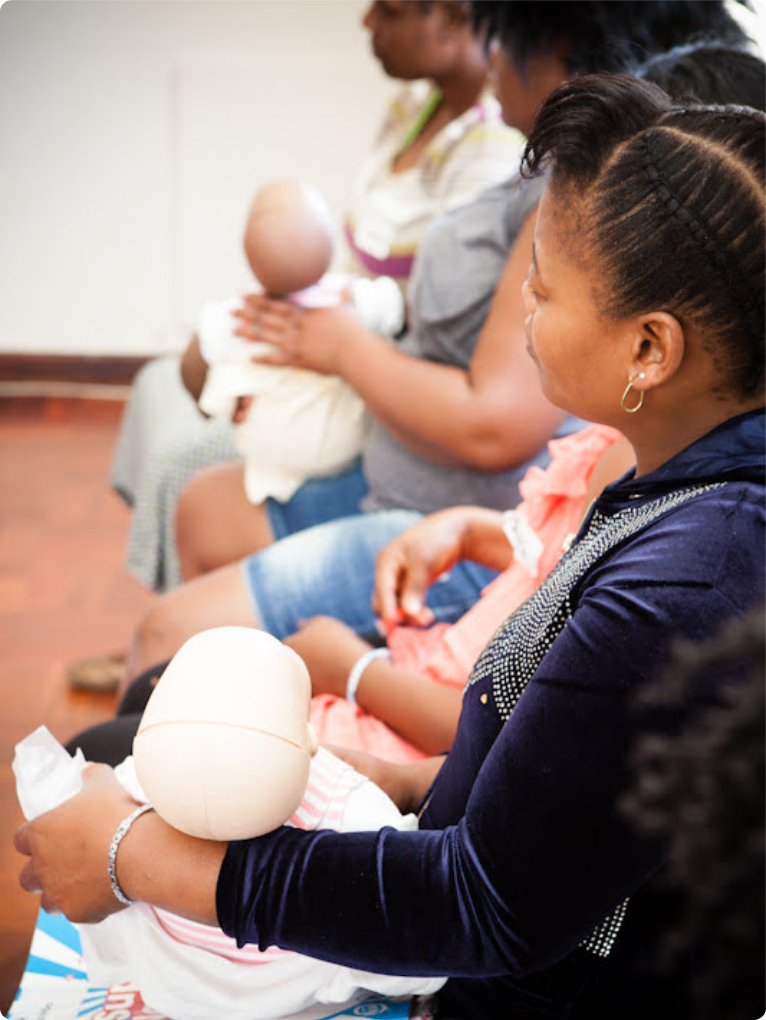 Nannies practising infant care techniques with training dolls