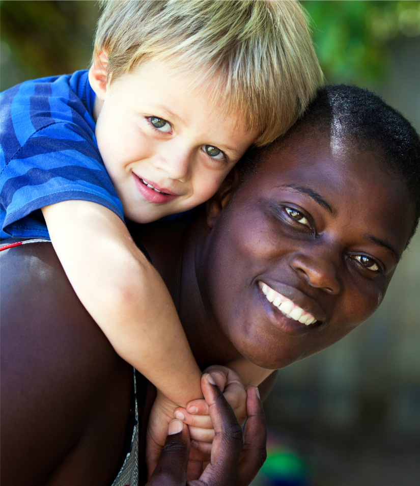 A smiling nanny giving a young child a piggyback hug
