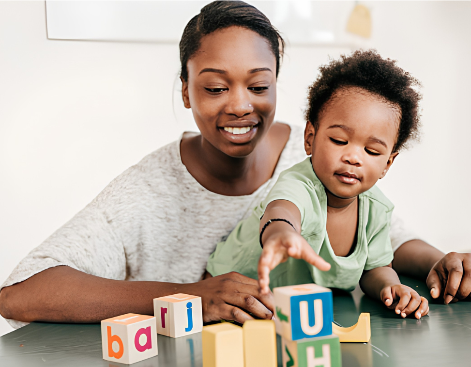 A nanny playing with letter blocks alongside a toddler
